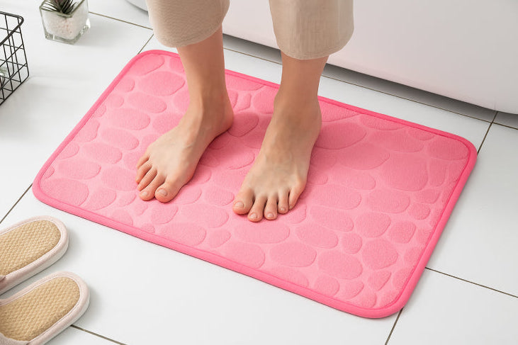 Tapis de bain mémoire de forme galet rose pieds 